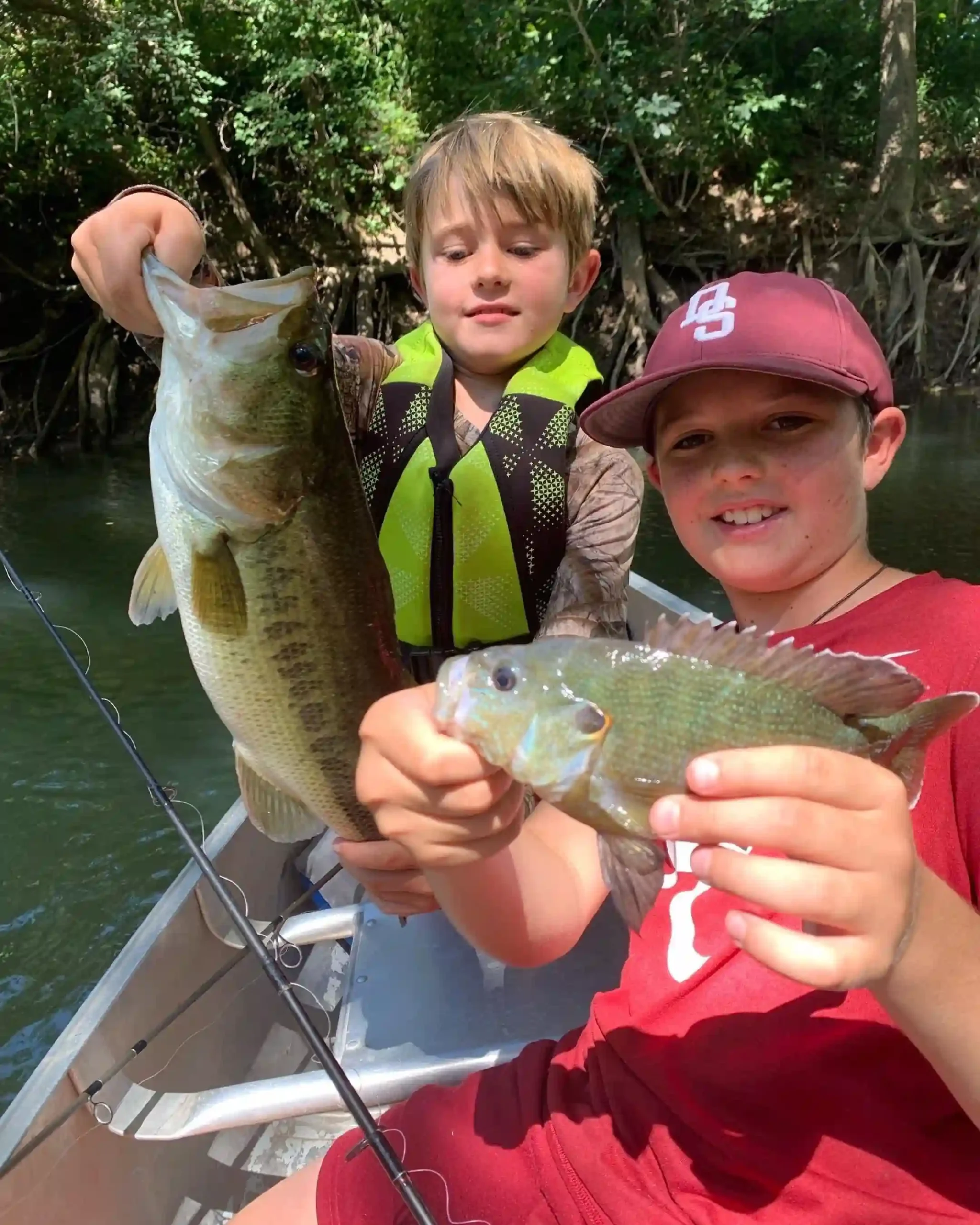 Two young boys holding fish, participating in Hill Country Fishing Camps' summer camp.