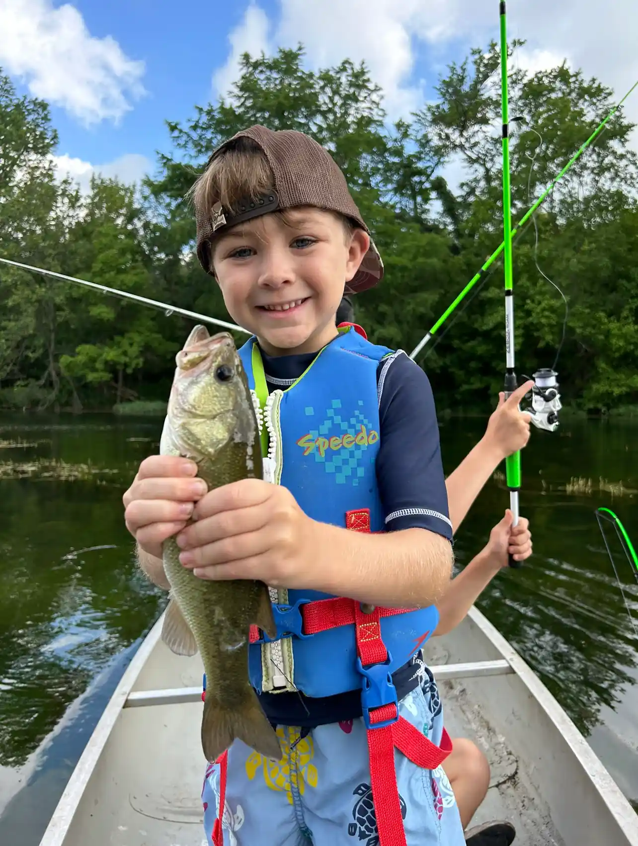 A young boy holding a fish, participating in Hill Country Fishing Camps' summer camp.